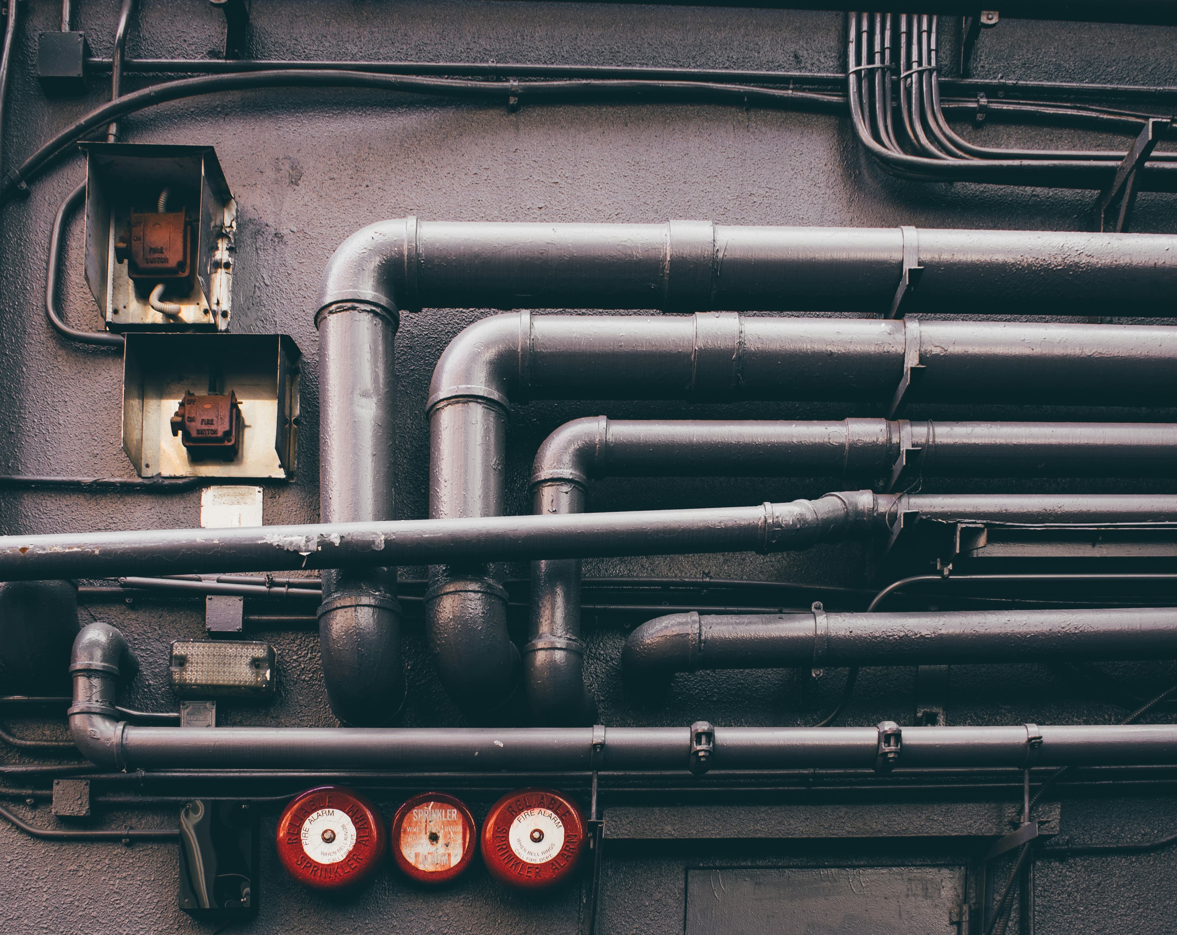 Dark industrial pipework fitted with red pressure gauges