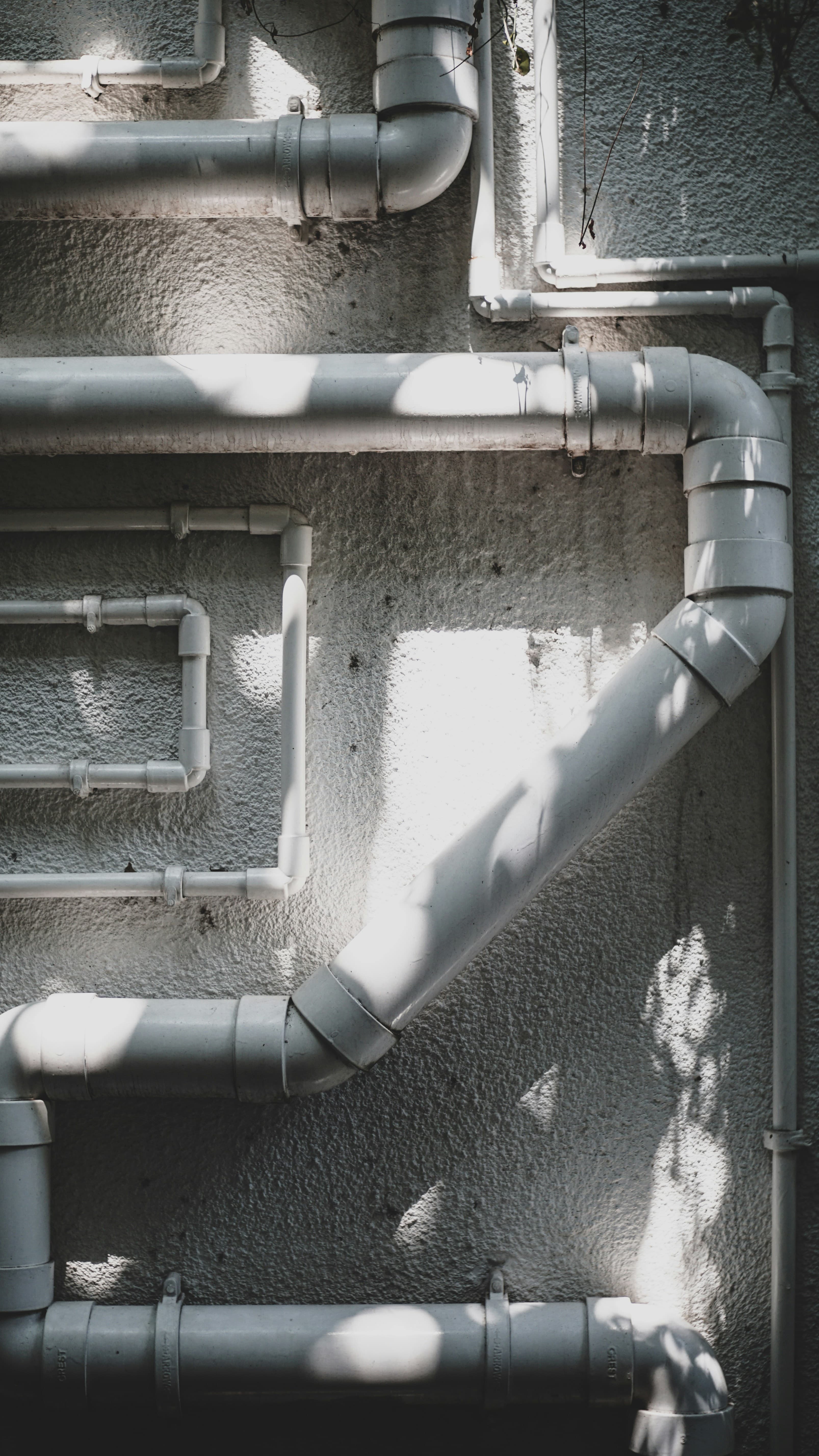 White pipe runs on concrete lit by hard sunlight
