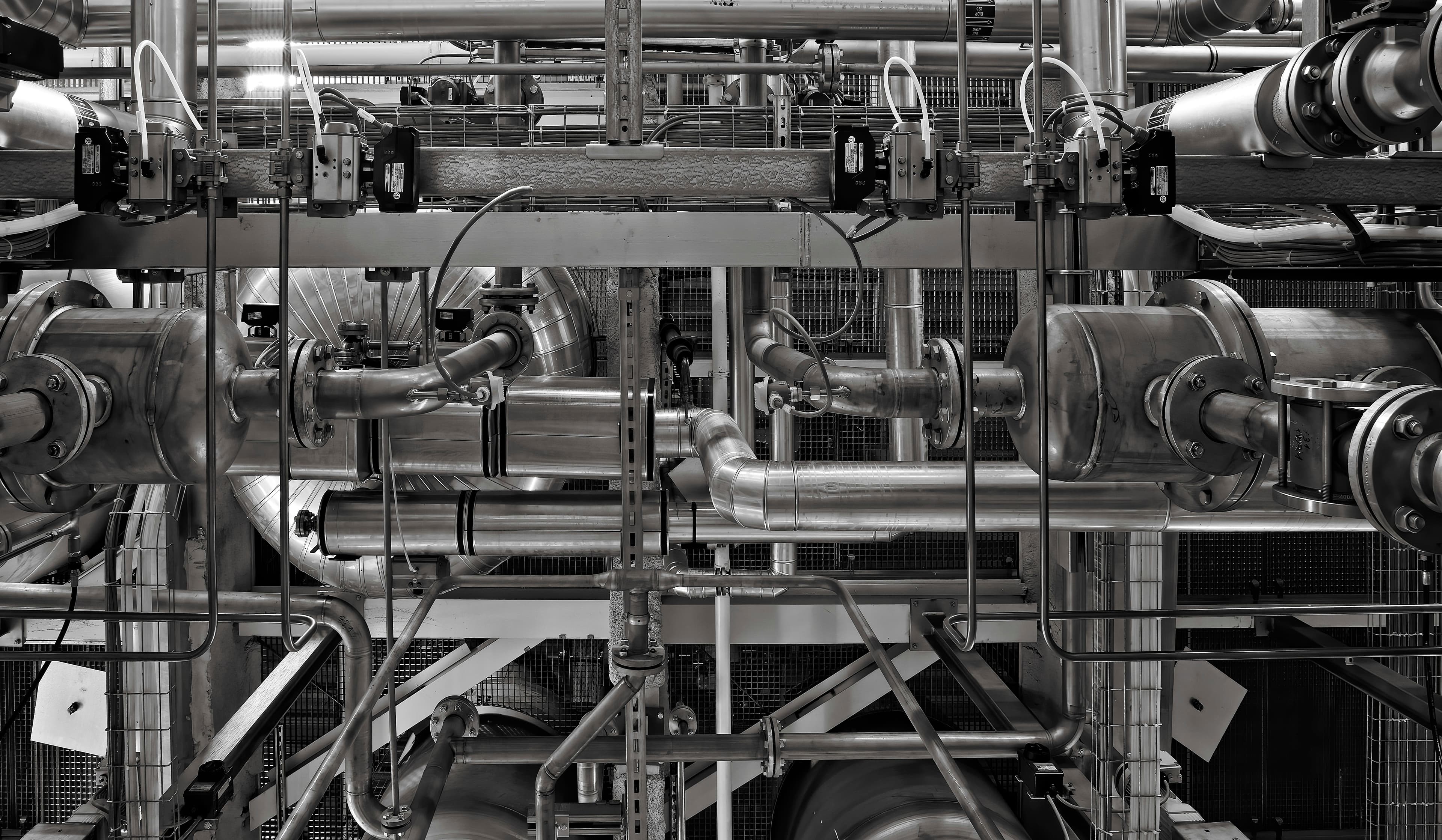 Dense industrial machinery and flanged joints in monochrome